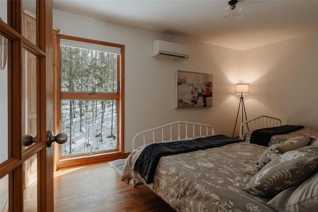 Bedroom featuring multiple windows, hardwood / wood-style flooring, and a wall mounted AC | Image 16