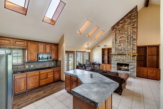 Kitchen with stainless steel appliances, a skylight, dark countertops, a sink, and high vaulted ceiling | Image 6