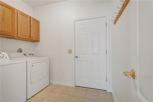 Laundry area featuring washing machine and dryer, baseboards, light tile patterned flooring, and cabinet space | Image 16