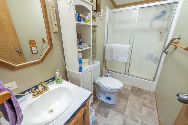 Full bathroom featuring toilet, stone finish flooring, vanity, and shower / bath combination with glass door | Image 21