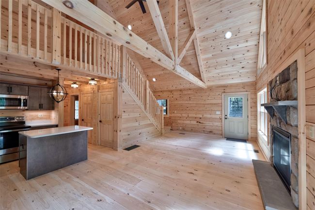 Kitchen featuring appliances with stainless steel finishes, wood ceiling with exposed beams, wooden walls, light wood finished floors, and a kitchen island | Image 10