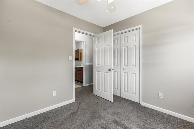 Unfurnished bedroom featuring dark carpet, baseboards, a closet, and a ceiling fan | Image 49