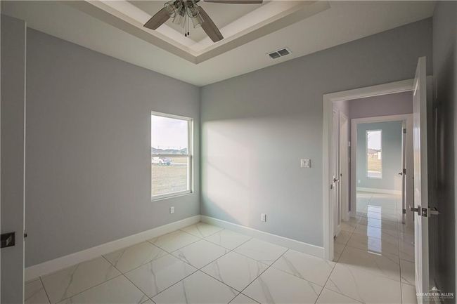 Spare room featuring a raised ceiling, a healthy amount of sunlight, and ceiling fan | Image 16