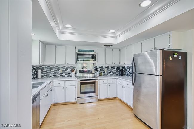Kitchen with stainless steel appliances, decorative backsplash, light countertops, ornamental molding, and recessed lighting | Image 15