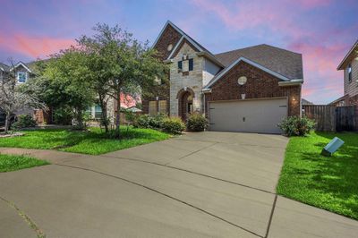 The spacious front yard features a well-maintained lawn and a charming brick and stone facade, highlighting the home's elegant architecture. | Image 2