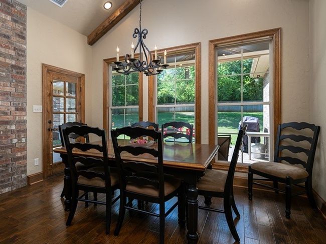 Dining area featuring dark wood finished floors, an inviting chandelier, vaulted ceiling with beams, and baseboards | Image 12