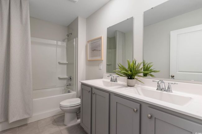 Bathroom with shower / bath combo with shower curtain, a sink, double vanity, and toilet | Image 25
