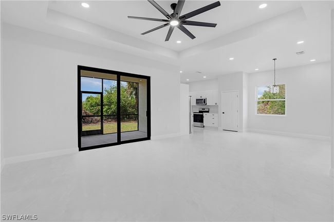 Empty room featuring a healthy amount of sunlight, ceiling fan, and a raised ceiling | Image 15