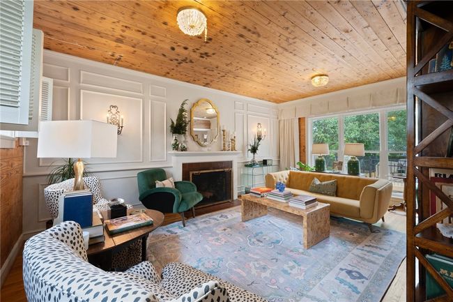 Living area featuring a decorative wall, wooden ceiling, a fireplace, wood finished floors, and ornamental molding | Image 5