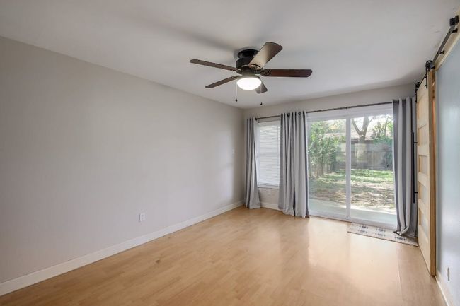 Empty room with a barn door, light wood finished floors, a ceiling fan, and baseboards | Image 29