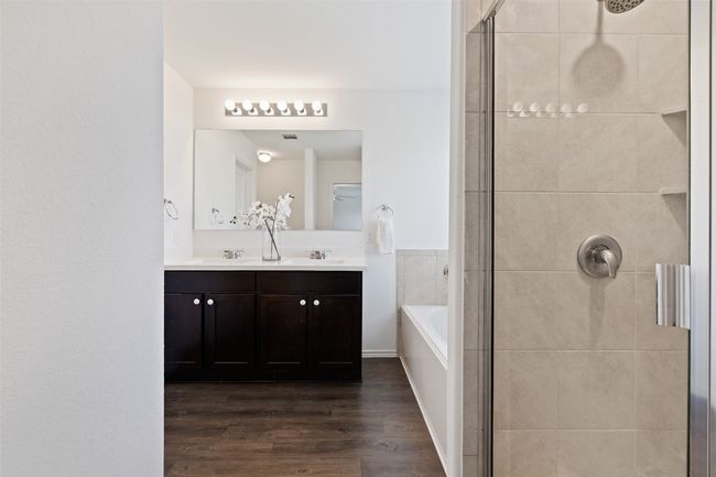 Bathroom featuring a shower stall, wood finished floors, double vanity, and a bath | Image 20