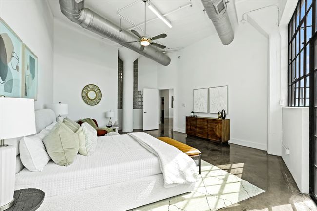 Bedroom featuring a towering ceiling, a ceiling fan, baseboards, and finished concrete floors | Image 25