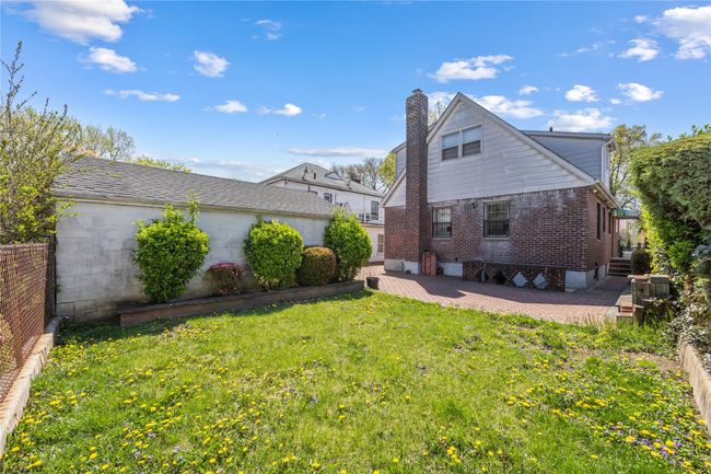 Back of property featuring fence, a chimney, a patio area, a lawn, and brick siding | Image 18