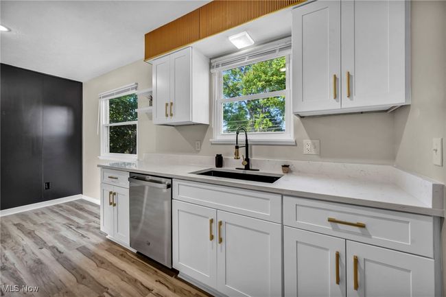 Kitchen with stainless steel dishwasher, open shelves, white cabinets, and light wood-style flooring | Image 11