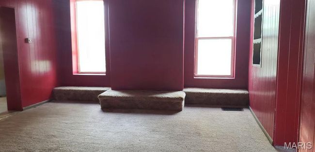 Unfurnished room featuring plenty of natural light, wooden walls, and carpet flooring | Image 6