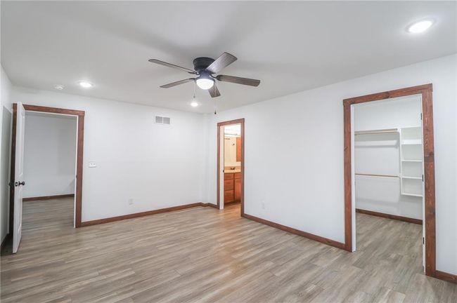 Unfurnished bedroom featuring ceiling fan, a closet, light hardwood / wood-style floors, and a walk in closet | Image 22