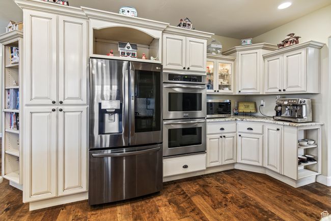 Kitchen featuring white cabinets, appliances with stainless steel finishes, dark hardwood / wood-style floors, and light stone counters | Image 32