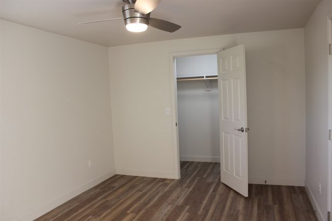 Unfurnished bedroom with dark wood-style flooring, ceiling fan, and a walk in closet | Image 17