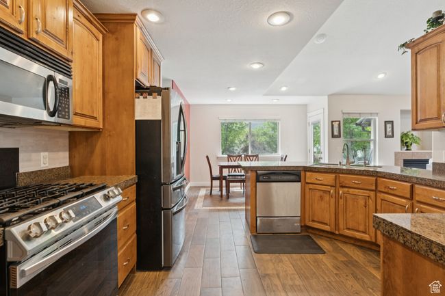 Kitchen featuring stainless steel appliances, brown cabinets, wood finished floors, and recessed lighting | Image 11