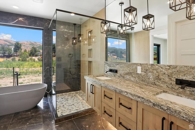 Full bathroom featuring a chandelier, marble tiled floors, a shower stall, a soaking tub, and double vanity | Image 30