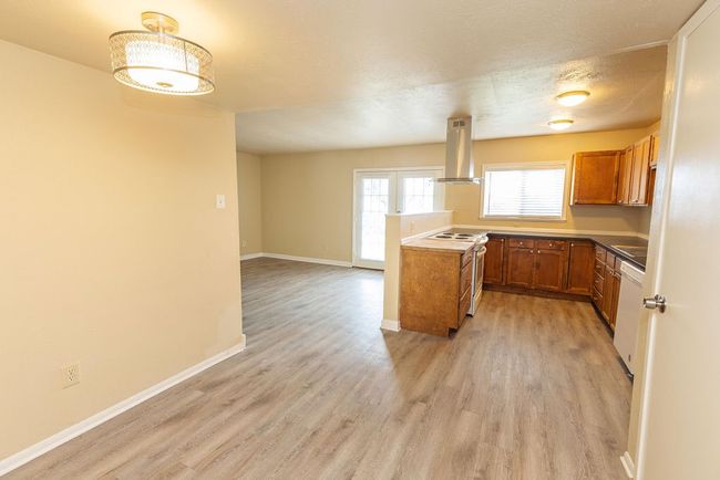 Kitchen featuring white appliances, french doors, a textured ceiling, range hood, and light hardwood / wood-style floors | Image 10