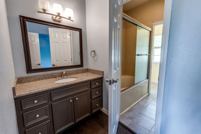 Full bathroom featuring baseboards, bath / shower combo with glass door, tile patterned flooring, and vanity | Image 26