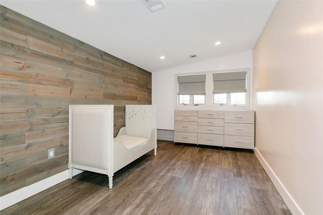 Sitting room with lofted ceiling, visible vents, baseboards, wooden walls, and wood finished floors | Image 18