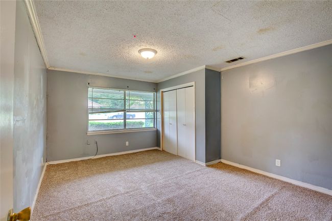 Unfurnished bedroom featuring crown molding, a textured ceiling, carpet flooring, a closet, and baseboards | Image 25