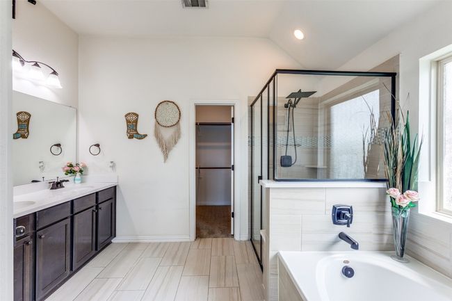 Full bath featuring a stall shower with rain shower head, double vanity, a bath, a spacious closet, and vaulted ceiling | Image 15