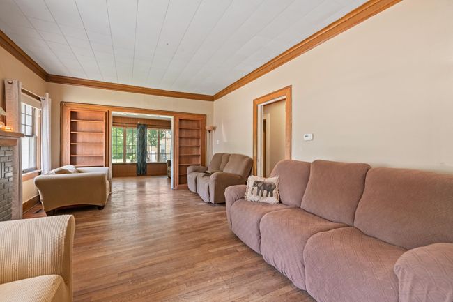 Living area featuring crown molding, light wood-style flooring, and a fireplace | Image 25