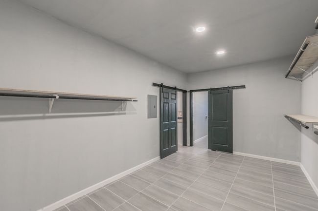 Walk in closet featuring light tile patterned flooring, a barn door, and electric panel | Image 12