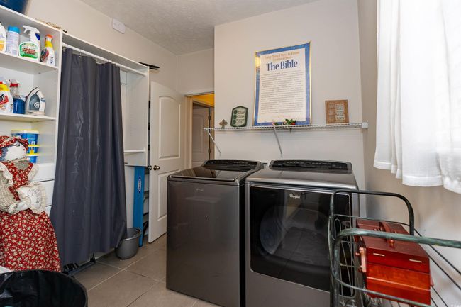Laundry room featuring light tile patterned flooring, a textured ceiling, washing machine and clothes dryer, and laundry area | Image 23