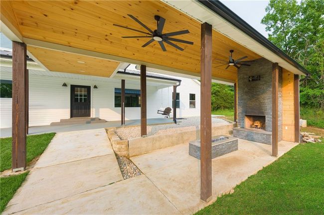 View of patio with an outdoor stone fireplace and ceiling fan | Image 70