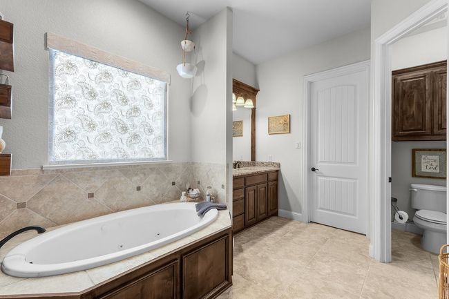 Full bath with toilet, vanity, a jetted tub, and tile patterned flooring | Image 18