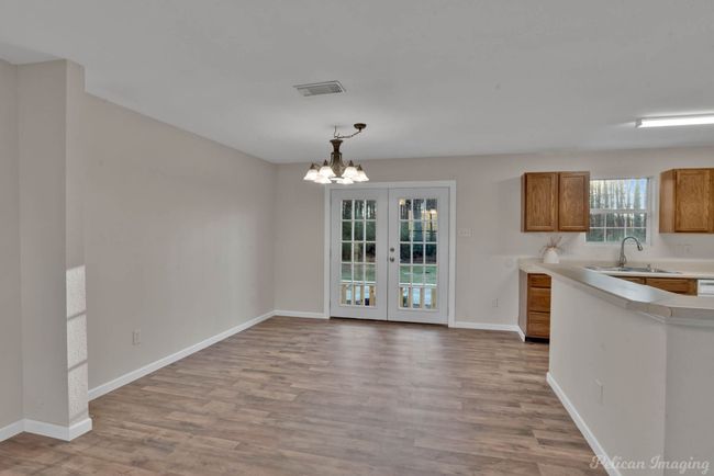 Unfurnished dining area featuring light hardwood / wood-style floors, french doors, a chandelier, and sink | Image 9