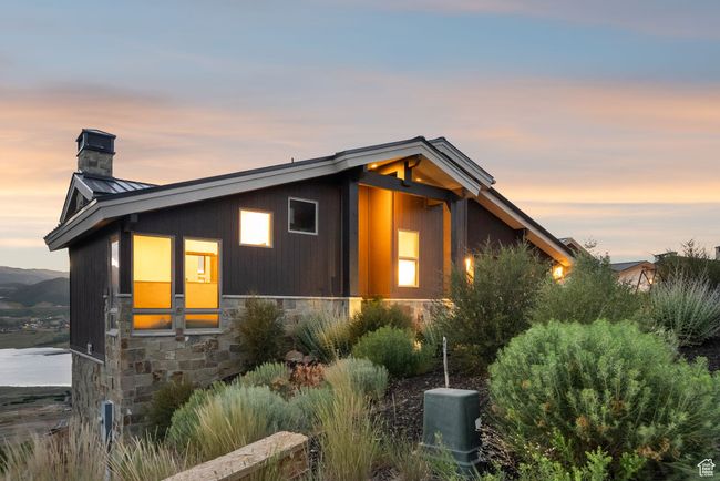 Property exterior at dusk with a chimney, a standing seam roof, stone siding, and a metal roof | Image 68