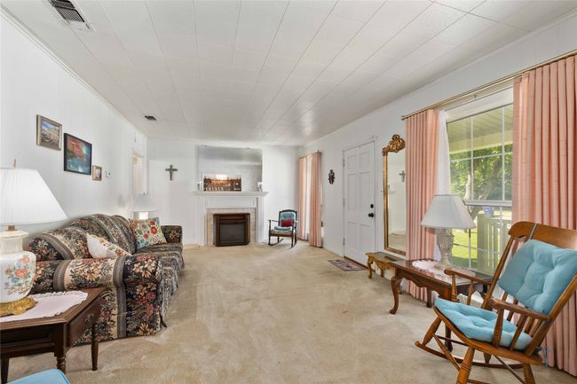 Living area featuring a freestanding fireplace surrounded by a decorative tiled fireplace. | Image 12