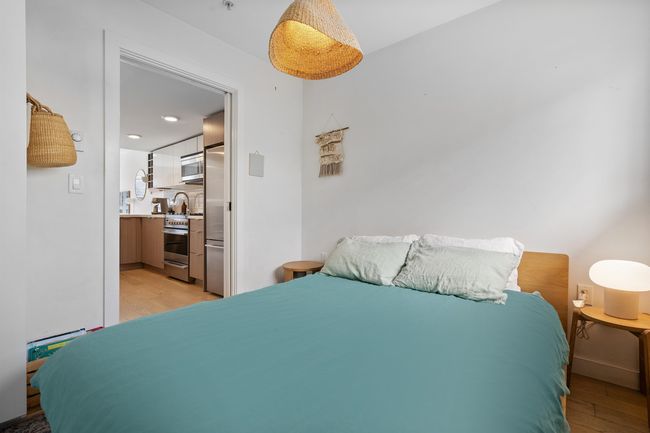 Bedroom with light wood-style floors, ensuite bathroom, baseboards, and stainless steel built in fridge | Image 16