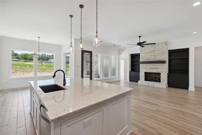 Kitchen featuring white cabinetry, an island with sink, sink, and light stone counters | Image 15