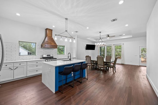 Kitchen featuring stainless steel gas range, premium range hood, tasteful backsplash, light countertops, and recessed lighting | Image 6
