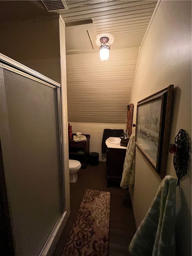 Full bathroom featuring a shower stall, wood ceiling, visible vents, and toilet | Image 28