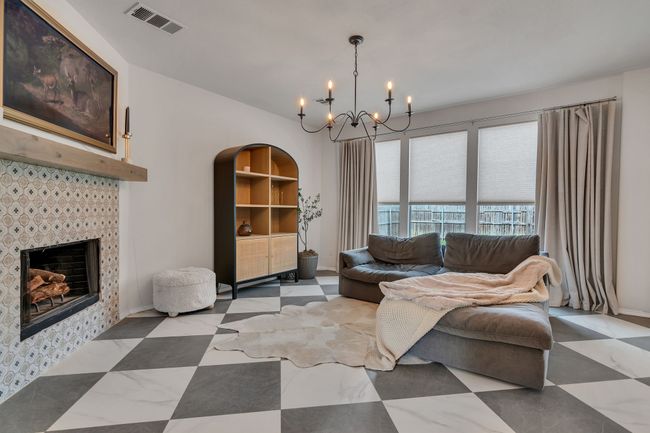 Living area with a chandelier, a tiled fireplace, and baseboards | Image 7