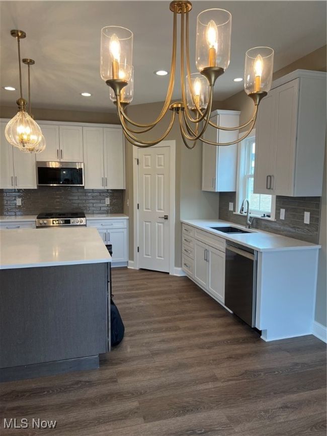 Kitchen with dishwasher, a chandelier, white cabinets, and recessed lighting | Image 4