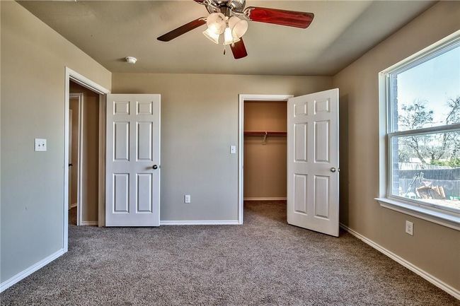 Unfurnished bedroom featuring carpet, a walk in closet, a ceiling fan, and a closet | Image 9