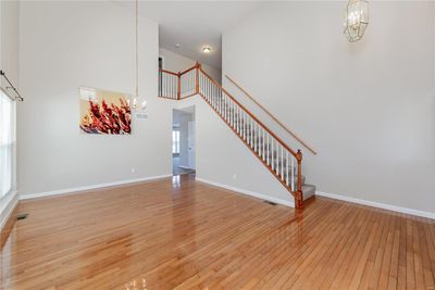 Unfurnished living room with a high ceiling, a notable chandelier, and light hardwood / wood-style floors | Image 3