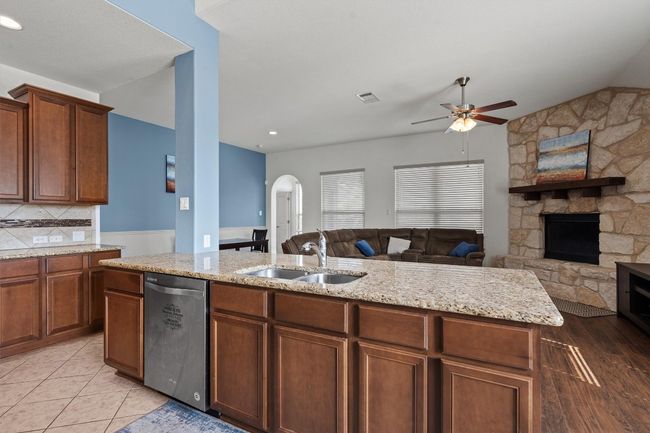 Kitchen featuring a sink, stainless steel dishwasher, open floor plan, a ceiling fan, and arched walkways | Image 6