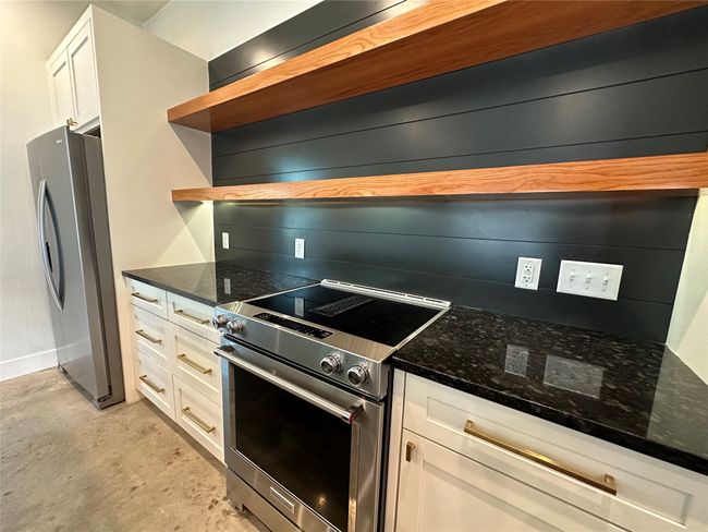 Kitchen featuring appliances with stainless steel finishes, open shelves, white cabinets, and dark stone counters | Image 26