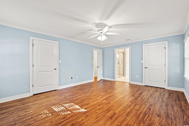 Unfurnished bedroom featuring ornamental molding, wood finished floors, ensuite bathroom, and a ceiling fan | Image 12