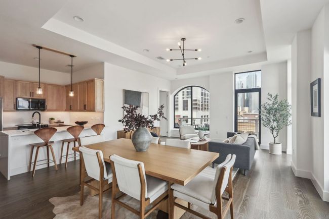 Dining space with a raised ceiling, a notable chandelier, dark wood finished floors, and baseboards | Image 5