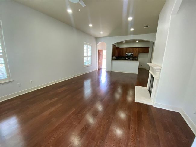 Unfurnished living room with arched walkways, dark wood-type flooring, recessed lighting, a ceiling fan, and baseboards | Image 7